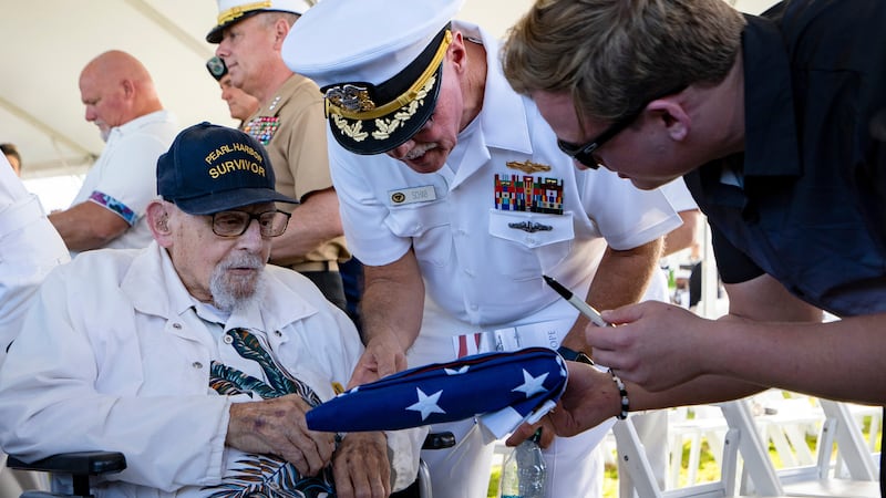 FILE - An attendee asks Pearl Harbor survivor Ira "Ike" Schab, 103, to sign an U.S. flag...