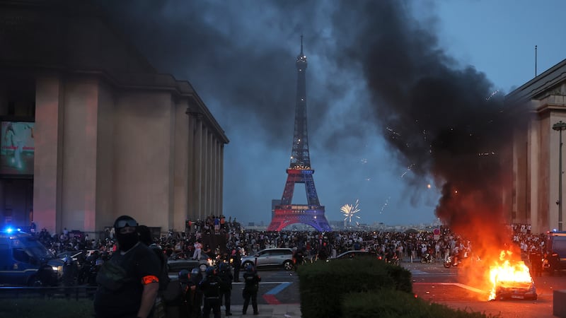 A car burns and fireworks explode as police watch PSG supporters celebrate in Paris, Saturday,...